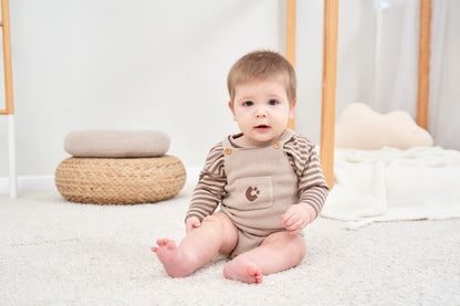 KNITTED SINGLESUIT - BEIGE; 100% Organic Cotton; Jacquard singletsuit made from GOTS-certified organic cotton; Features convenient press snaps at the crotch for effortless dressing; Rib finish and neck, armholes and leg opening.