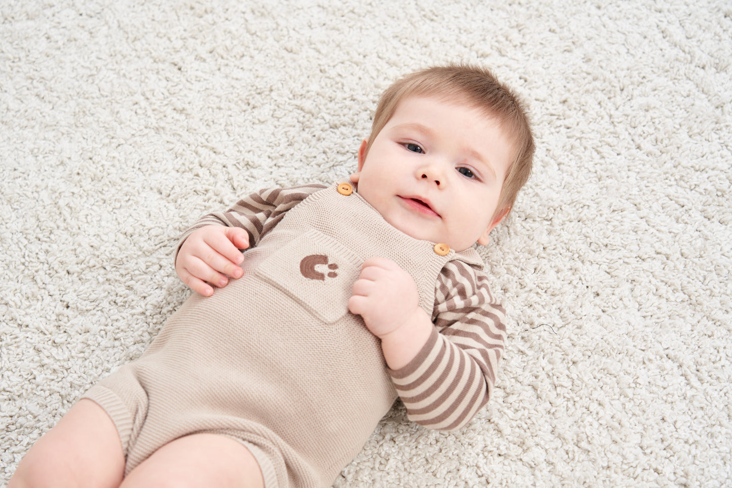 KNITTED SINGLESUIT - BEIGE; 100% Organic Cotton; Jacquard singletsuit made from GOTS-certified organic cotton; Features convenient press snaps at the crotch for effortless dressing; Rib finish and neck, armholes and leg opening.